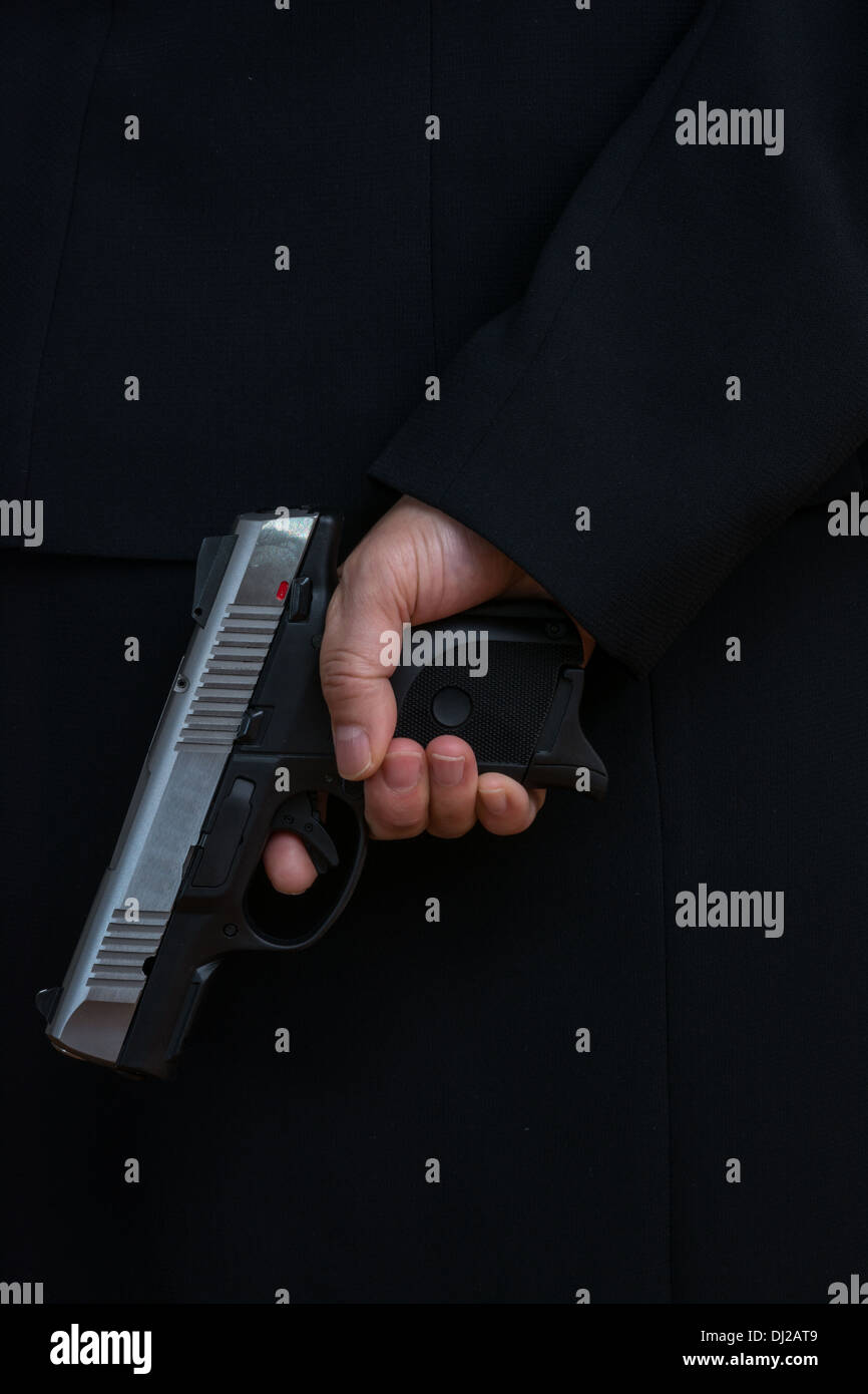 Nahaufnahme mit Frau im Business Anzug halten eine Pistole, dunkler Anzug Stockfoto