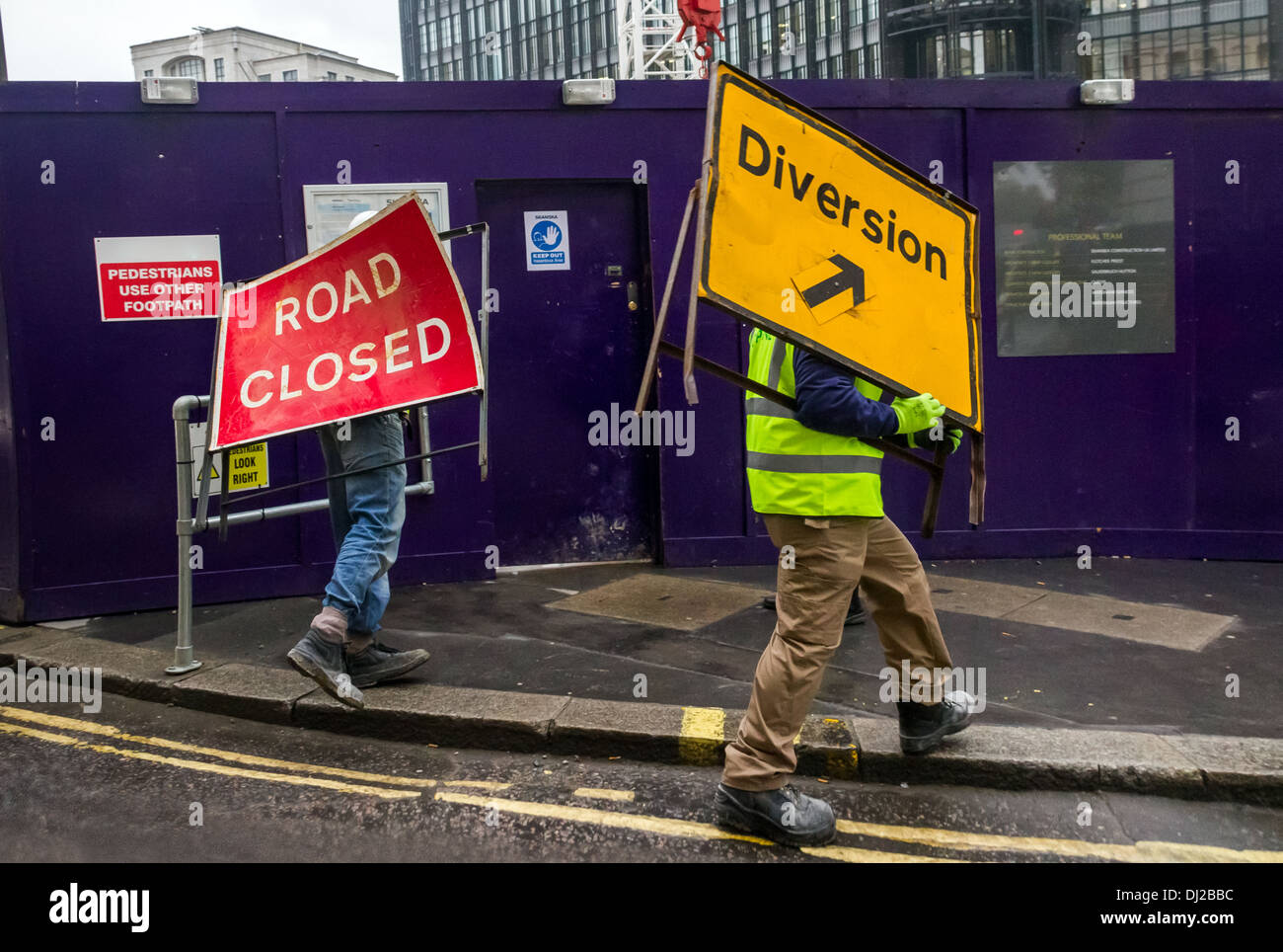 Zwei Arbeiter bewegen Straße geschlossen und der Abzweigung Zeichen in der Nähe einer Baustelle im Zentrum von London, UK. Stockfoto