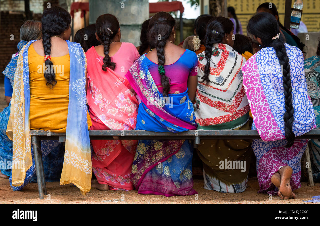 Linie von indischen Frauen tragen bunte Sari saß auf einer Bank. Andhra Pradesh, Indien Stockfoto