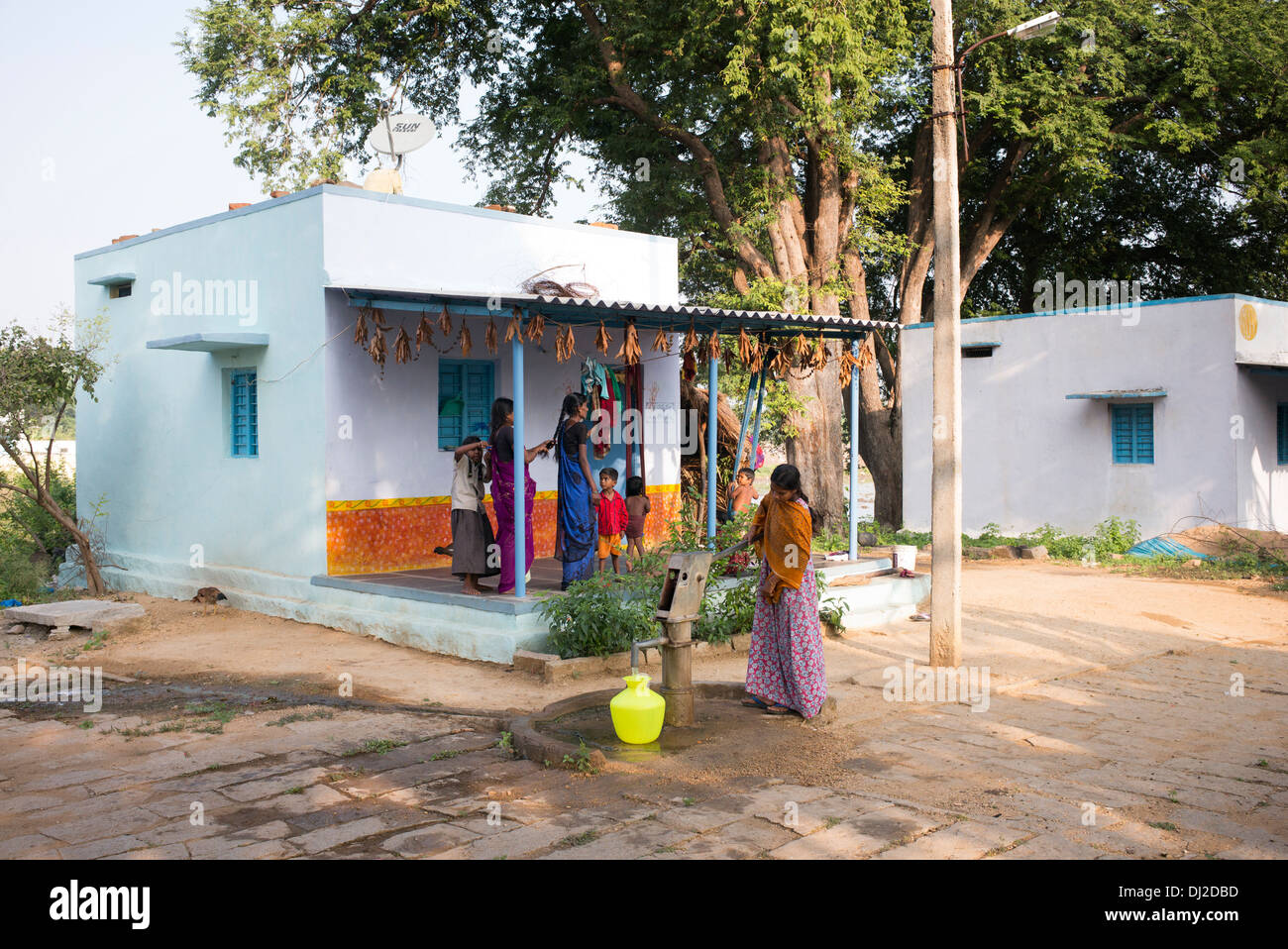 Indische Frau Füllung Kunststoff Wassertopf aus einem ländlichen Dorf Handpumpe. Andhra Pradesh, Indien Stockfoto