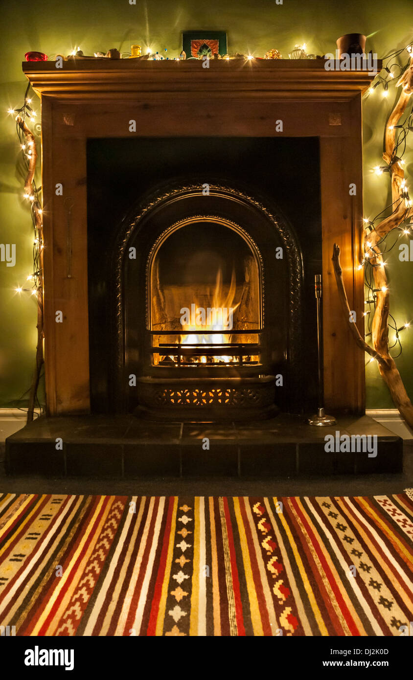 Eine wärmende, festliche Kamin mit Lichterketten und Teppich. Stockfoto
