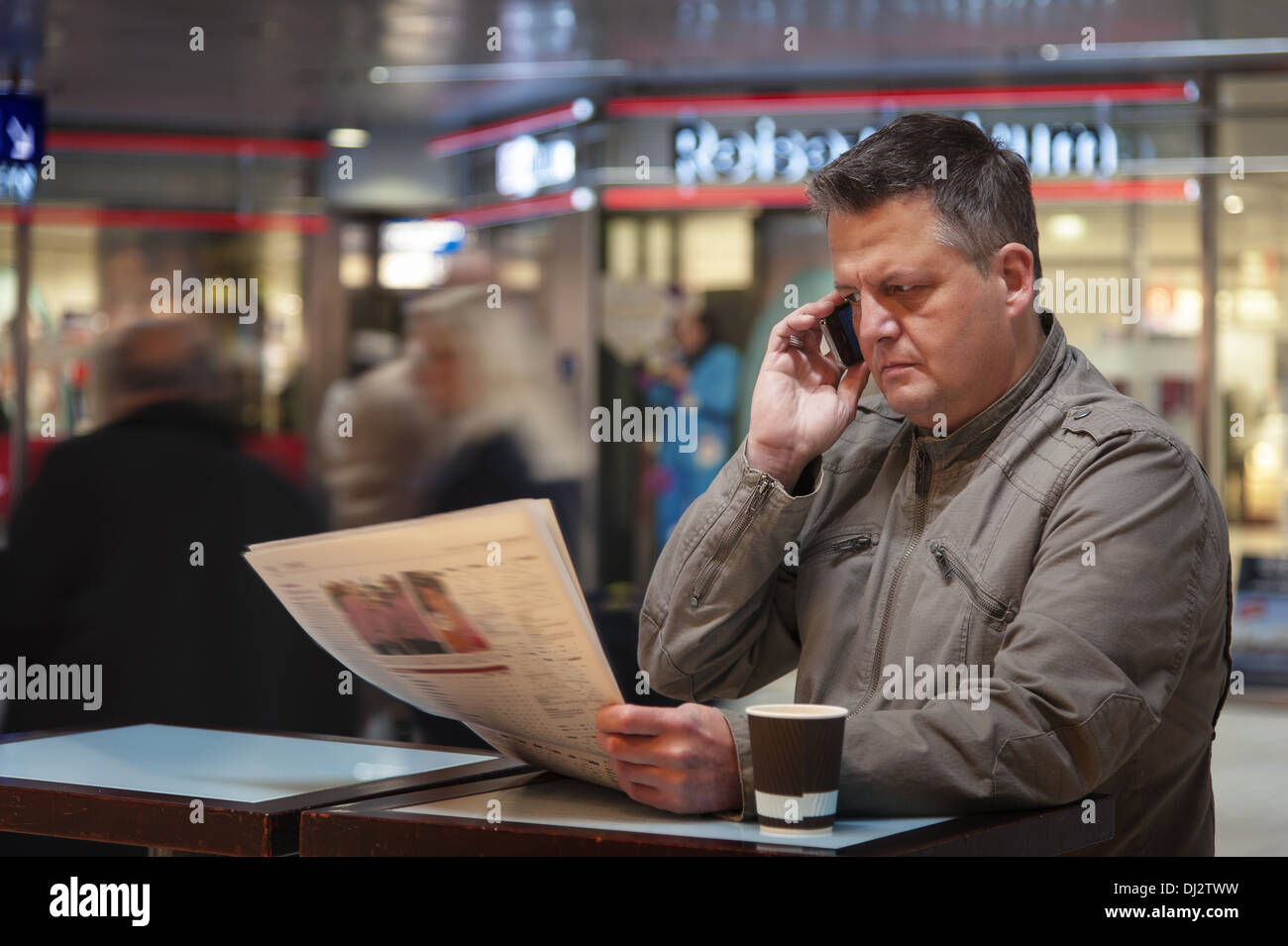 Telefonie machen Mann liest Zeitung Stockfoto