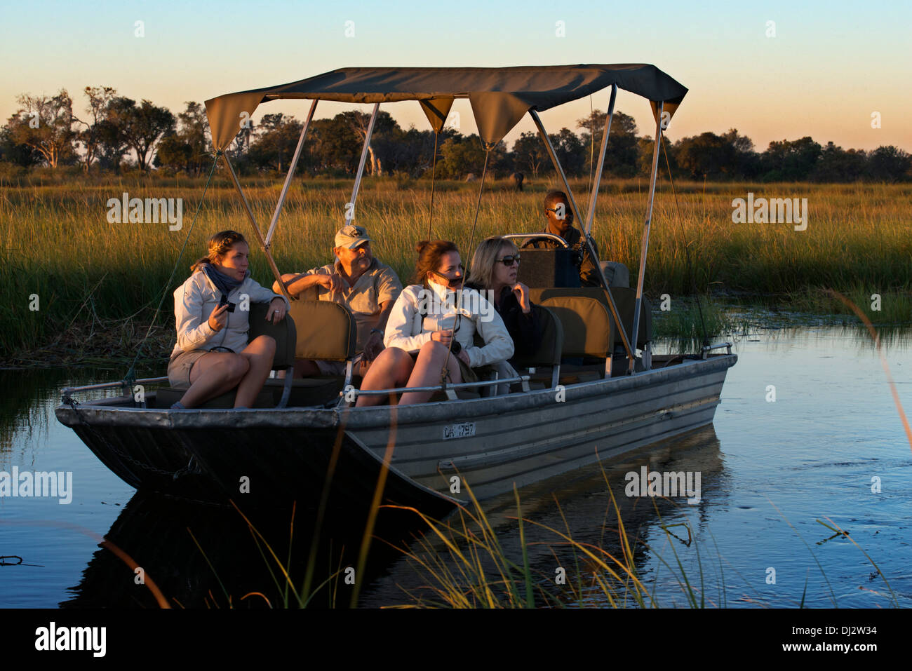 Touristen genießen die letzten Sonnenstrahlen auf dem Wasser-Safari-Camp von Eagle Island Camp von Orient-Express, außerhalb Moremi gemacht Stockfoto