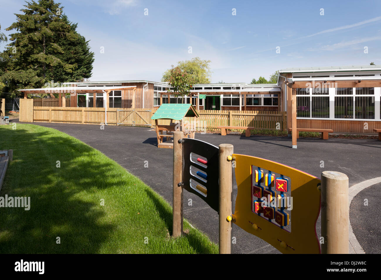 Kindergarten-Spielplatz mit outdoor-Ausrüstung vor Holz verkleidet einstöckigen Klassenräume. Stockfoto