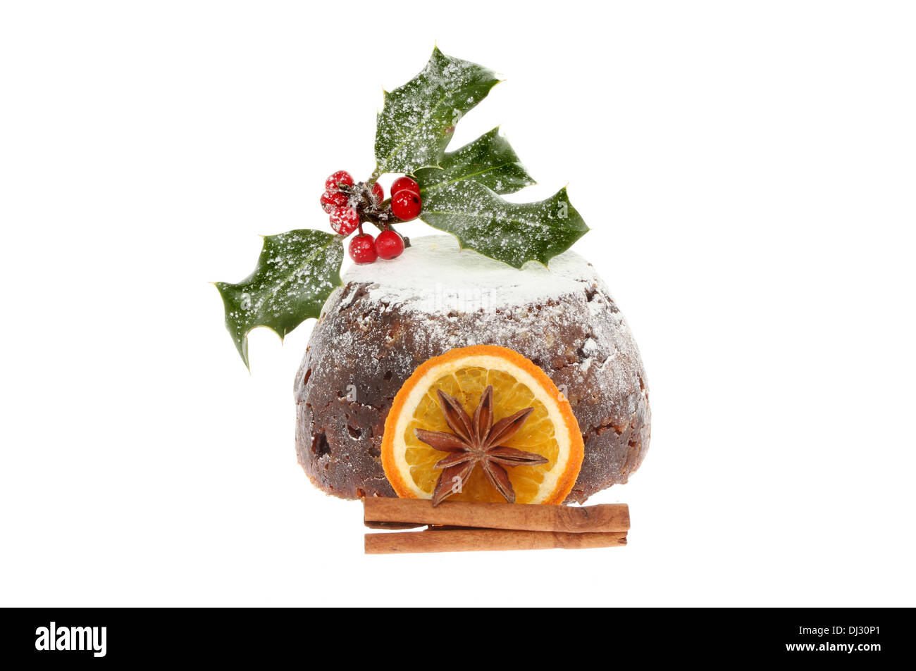 Christmas Pudding mit Puderzucker bestäubt und dekoriert mit Gewürz und Holly isoliert gegen weiß Stockfoto