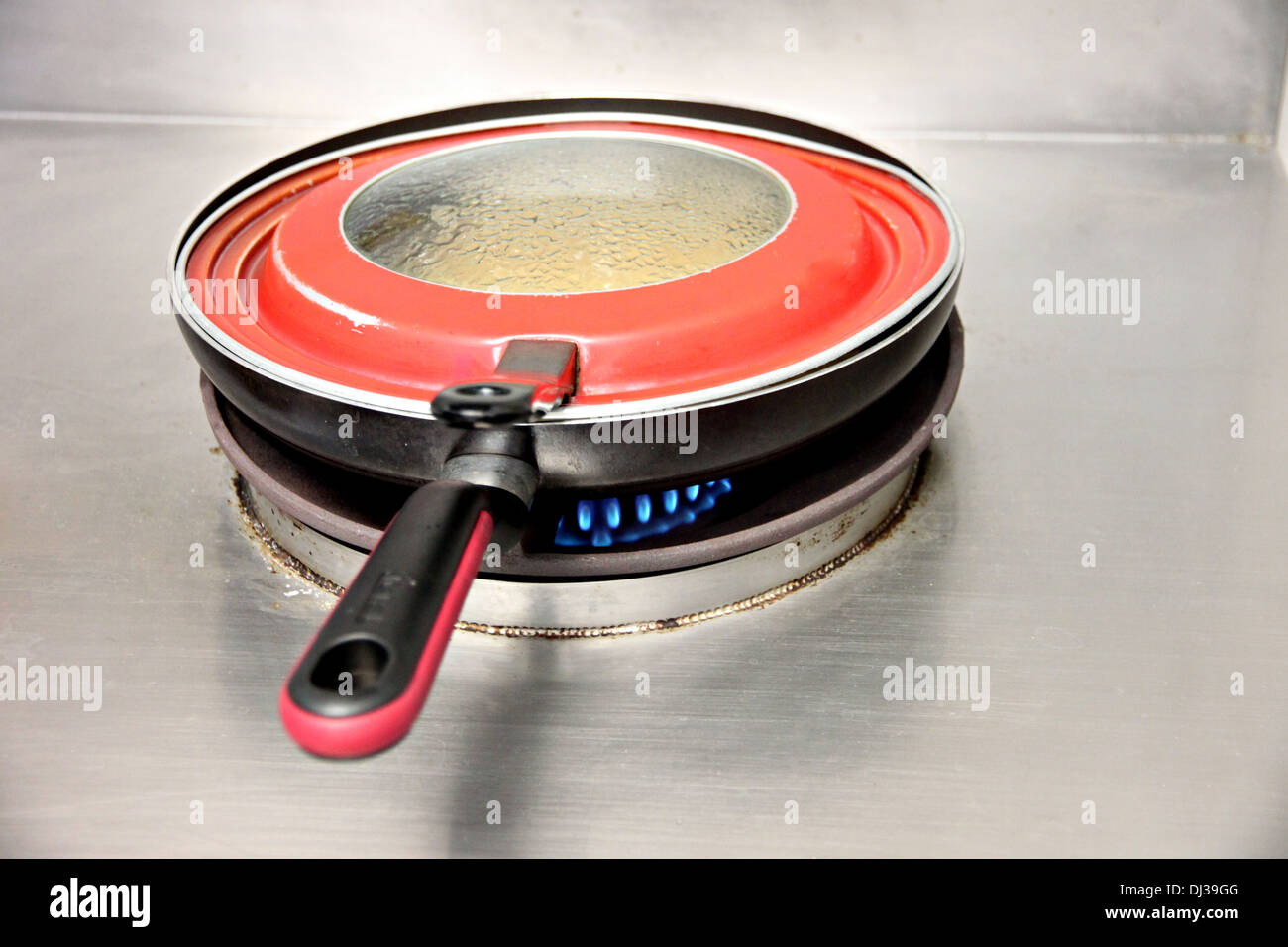 Rote Pfanne war auf dem Herd in der Küche kochen. Stockfoto