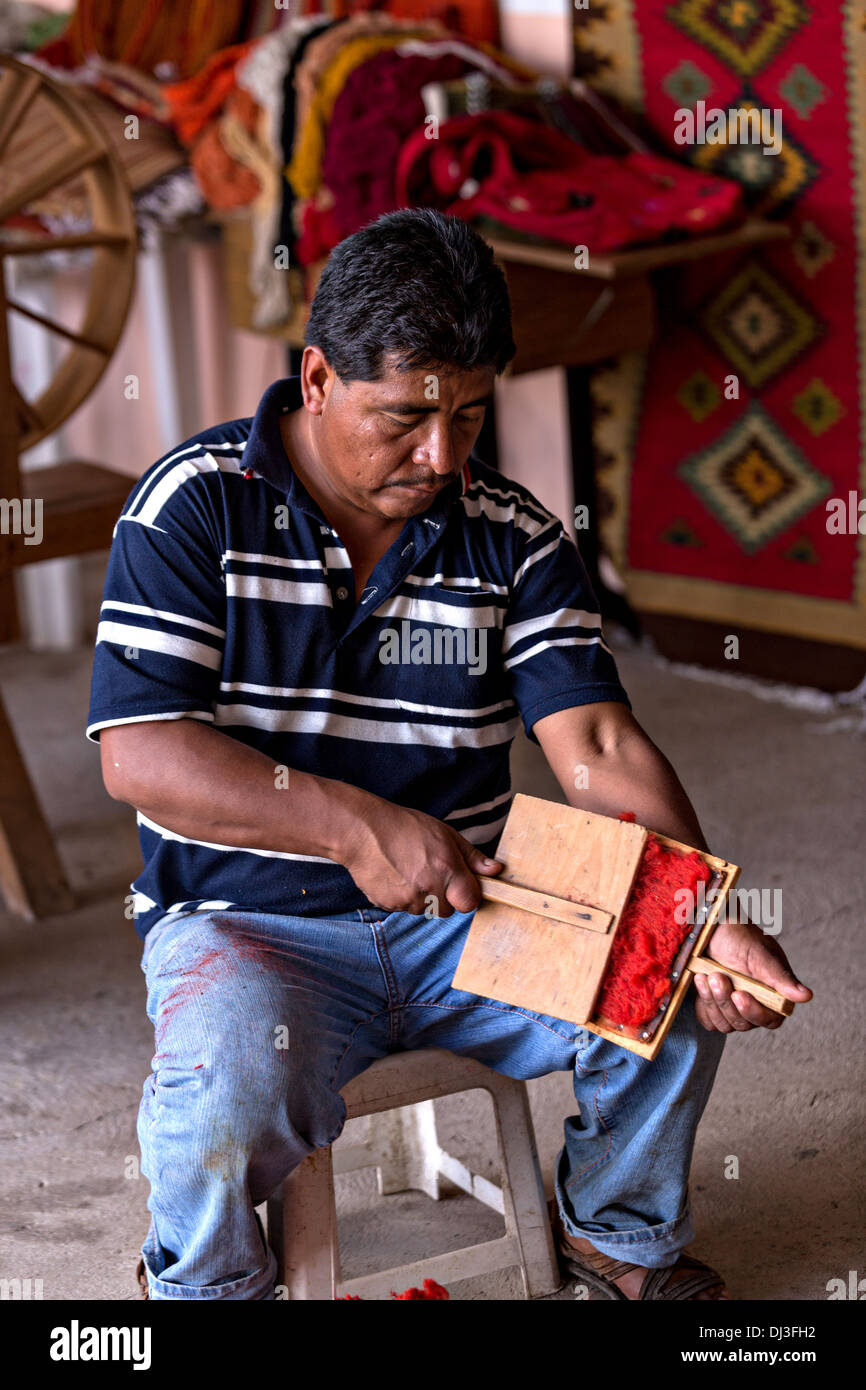 Ein zapotekischen indigenen Mann Handkarten gefärbte Wolle zu Garn verwendet werden, in der Weberei traditionelle Teppiche in Teotitlan de Valle, Mexiko. Stockfoto