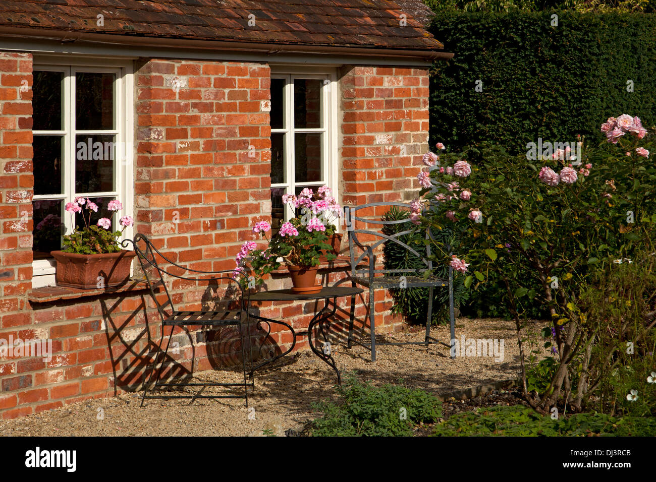 Viktorianische Backstein Hausgarten mit Rosen, UK und Metall Gartenmöbel Stockfoto