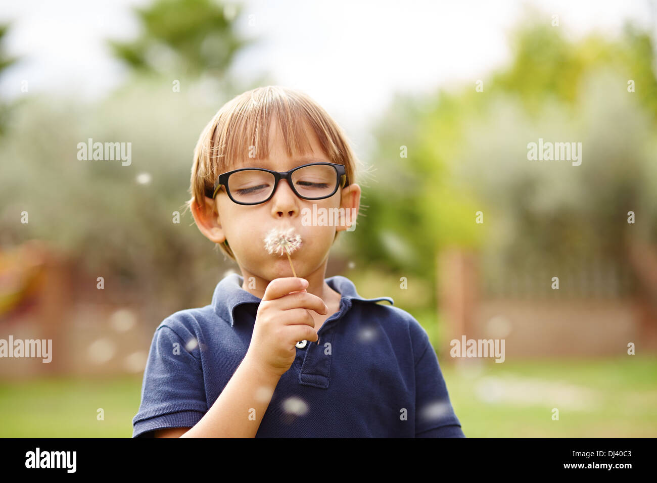 Kleiner Junge bläst einen Löwenzahn wünschen im freien Stockfoto