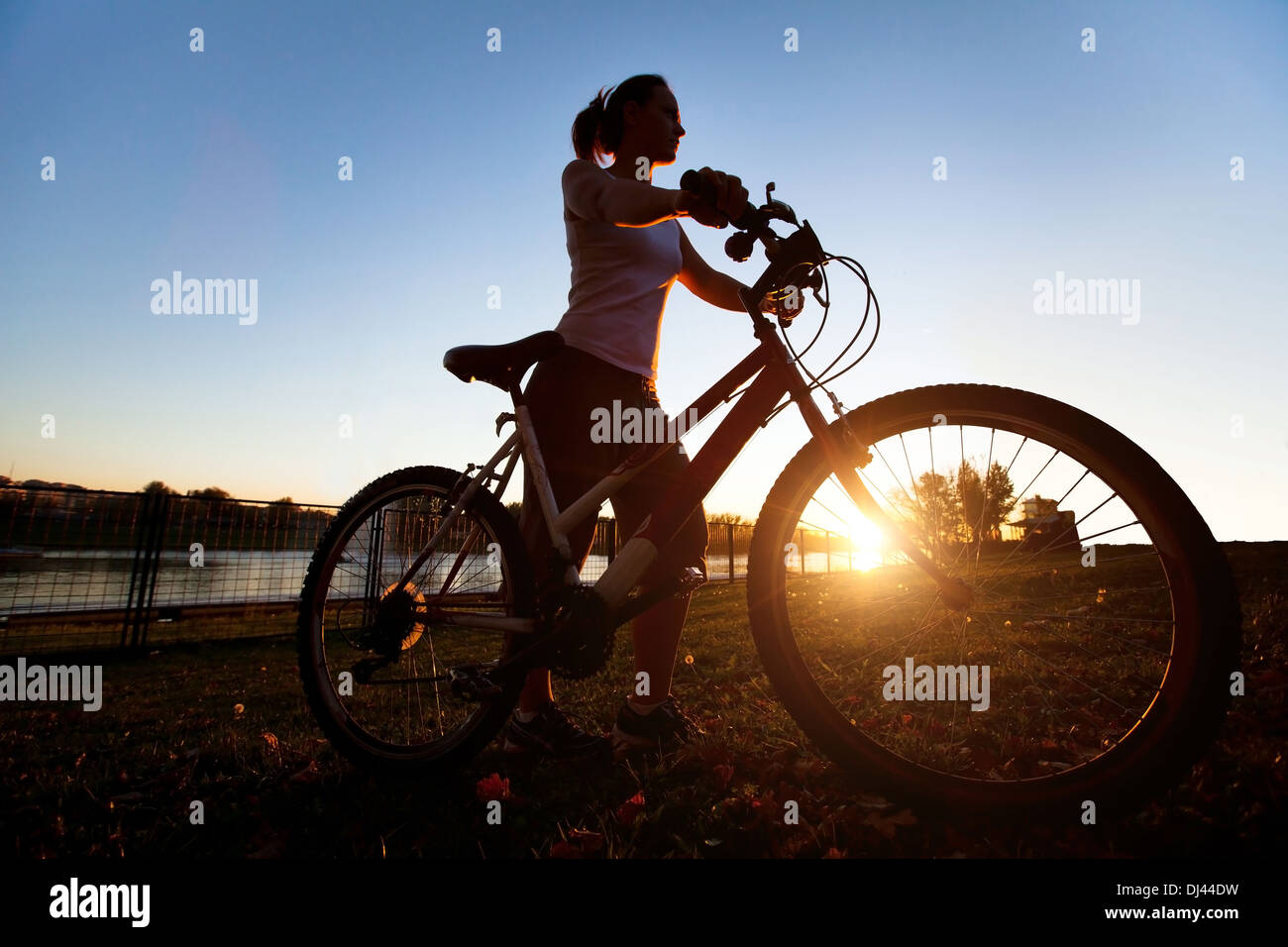 Silhouette der jungen Frau mit dem Fahrrad im freien Stockfoto