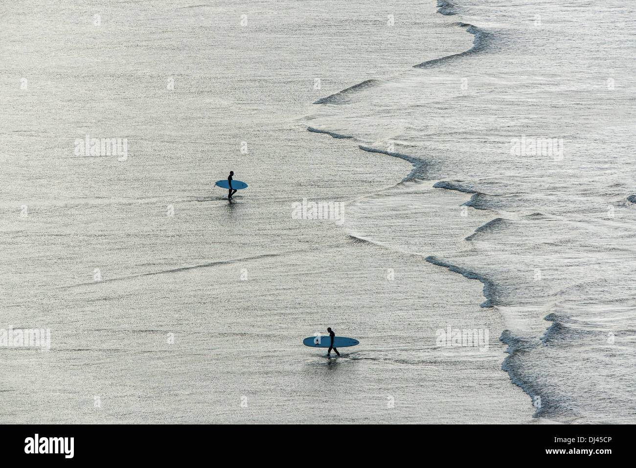 Silhouette Surfer im Bild gegen ein fast metallisches Reflexion des Lichtes auf dem Wasser im Saunton Sands Beach, Devon, UK Stockfoto