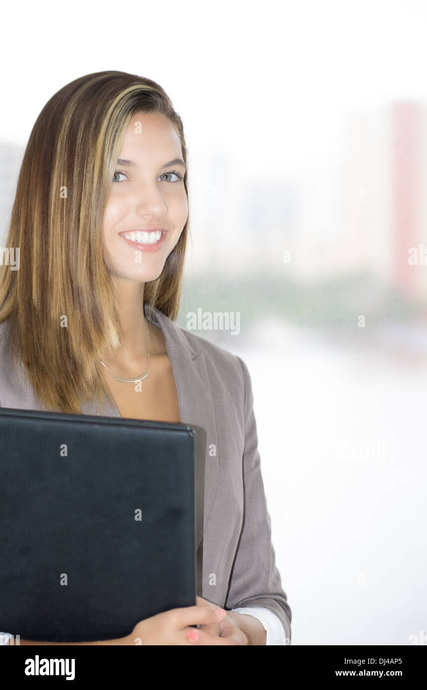 Junge Frau in der Wirtschaft Anzug mit Laptop mit einem Hauch von Vertrauen und Positivität. Stockfoto
