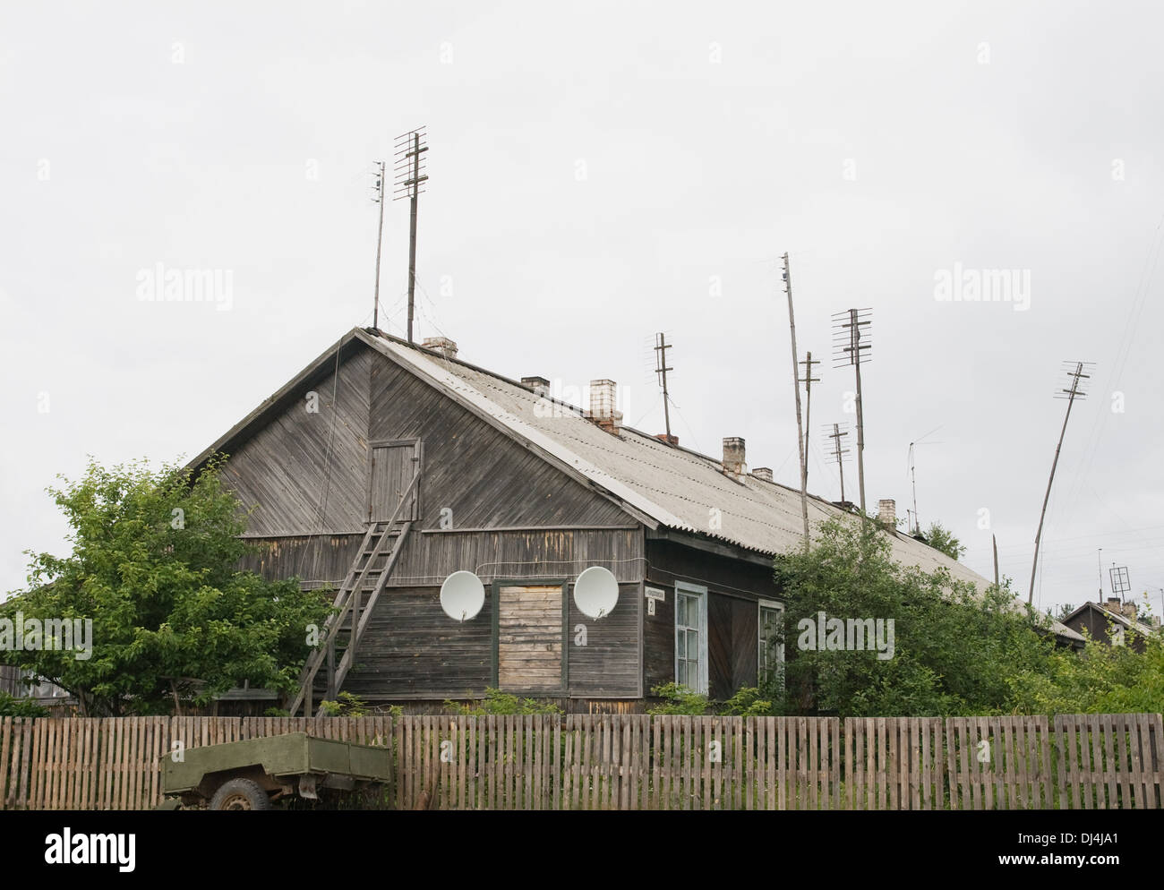 Ein altes Holzhaus mit vielen Antennen auf dem Dach Stockfoto
