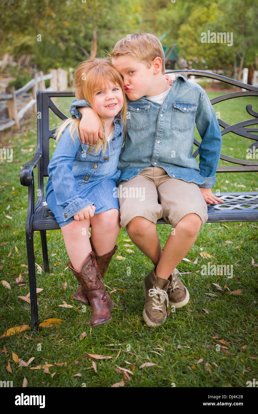 Happy Young Bruder und Schwester zusammen sitzen auf einer Bank außerhalb. Stockfoto