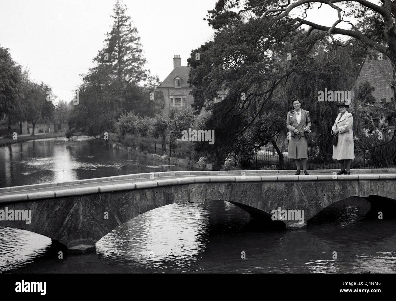 Historische Abbildung von 193os zwei Damen outdoor Jacken stehen auf einer kleinen Brücke über einen Fluss tragen. Stockfoto