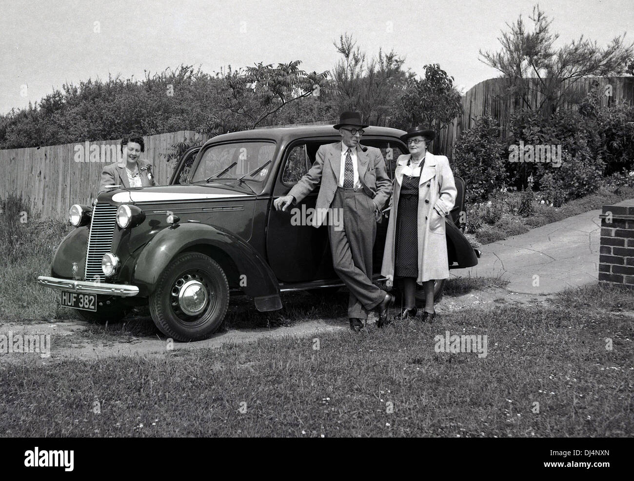 1940s, historisch, drei elegant gekleidete Menschen, die an einem Auto der damaligen Zeit in einer Auffahrt standen, England, Großbritannien. Stockfoto