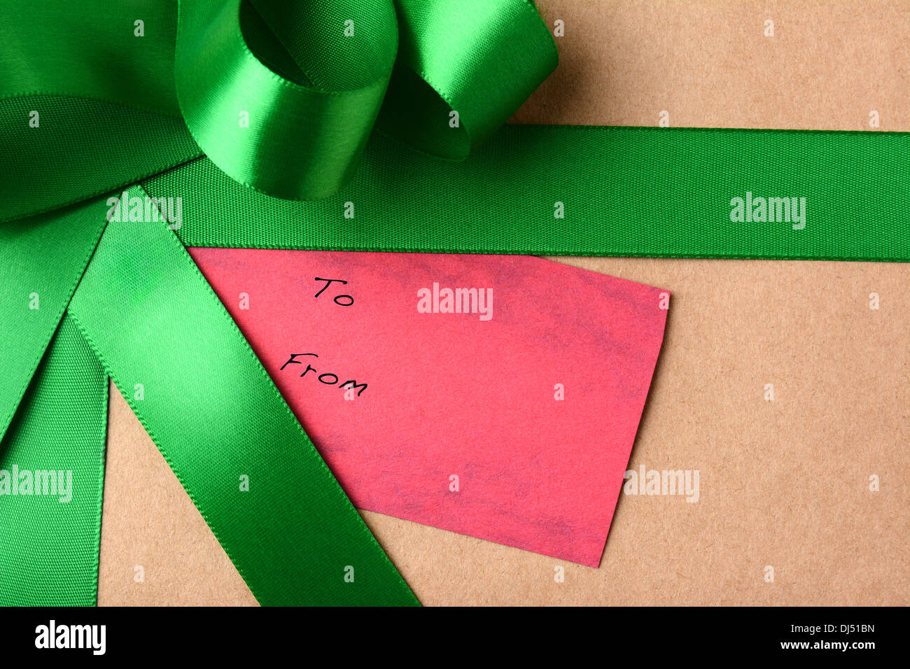 Nahaufnahme einer Geschenkanhänger auf ein Weihnachtsgeschenk. Das Paket ist umhüllt von braunen Normalpapier und Green Ribbon. Stockfoto