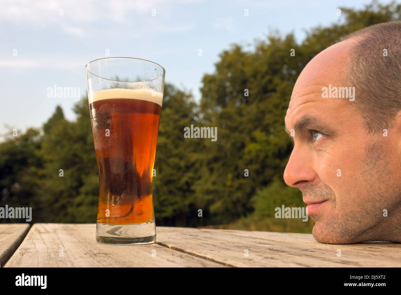 Ein Mann sucht sehnsüchtig auf ein Glas Bier. Stockfoto