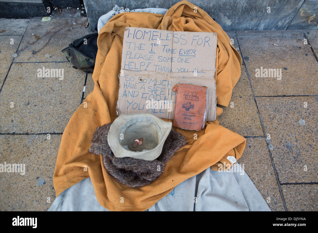 Obdachlose Person Bibel, Hut und Decken verlegt links auf der High Street, Großbritannien Stockfoto