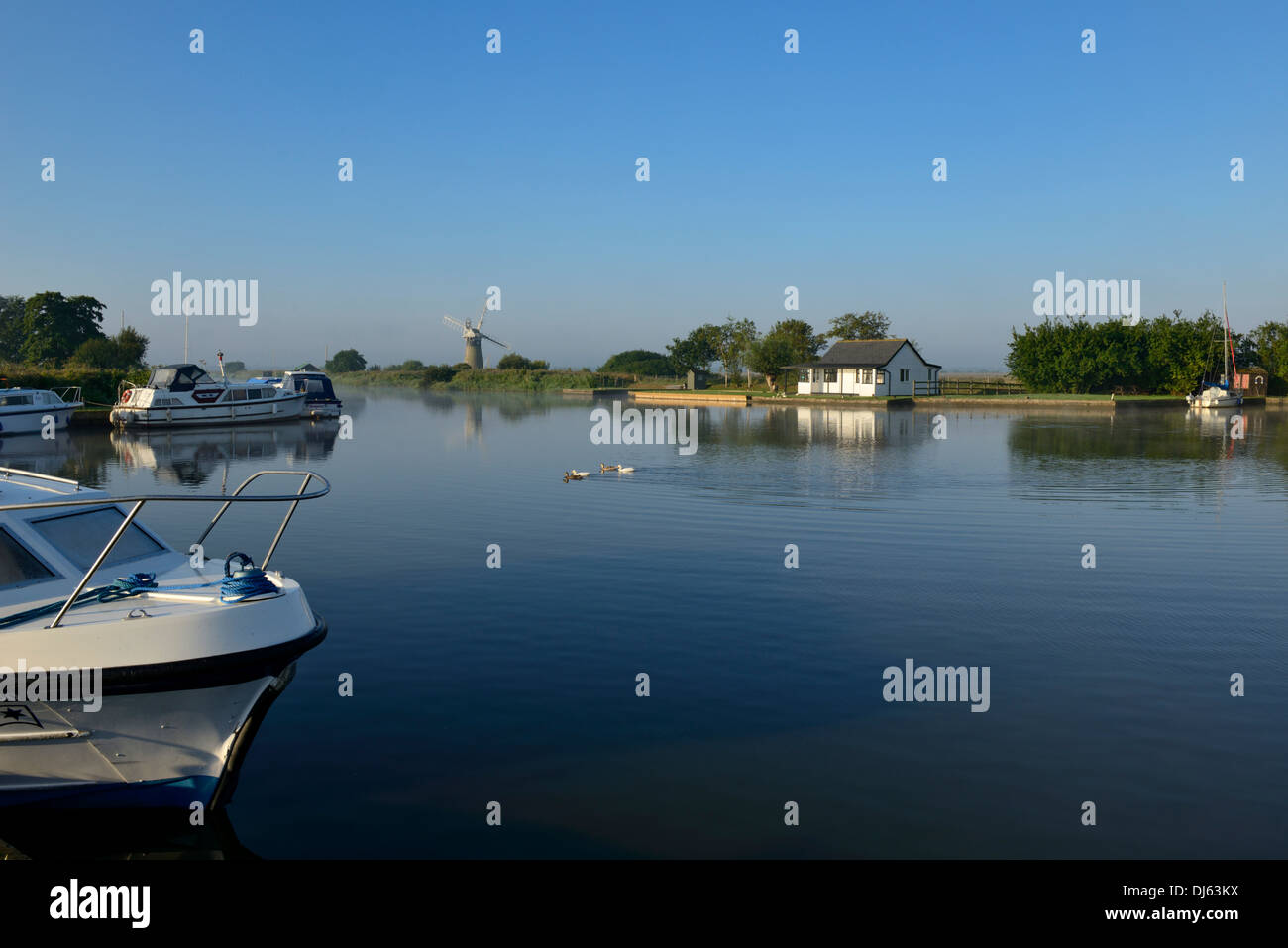 Freizeitboote und Windmühle im frühen Morgennebel und Sonnenschein auf dem Fluß Thurne, Thurne, Norfolk, England, UK, Europa Stockfoto