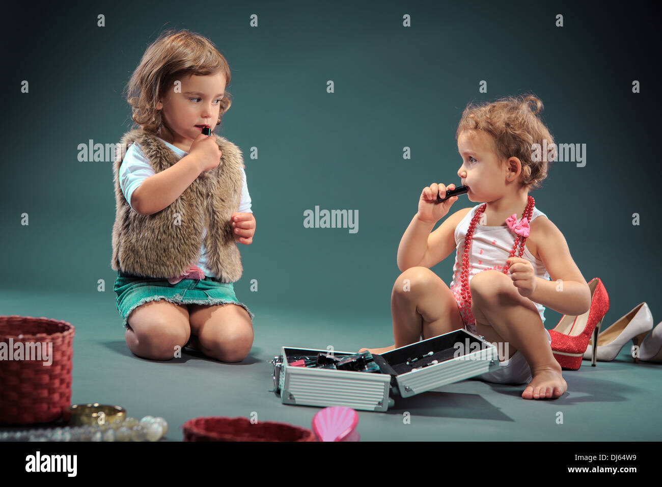Studioaufnahme von zwei kleinen Mädchen, die sich selbst schminken Stockfoto