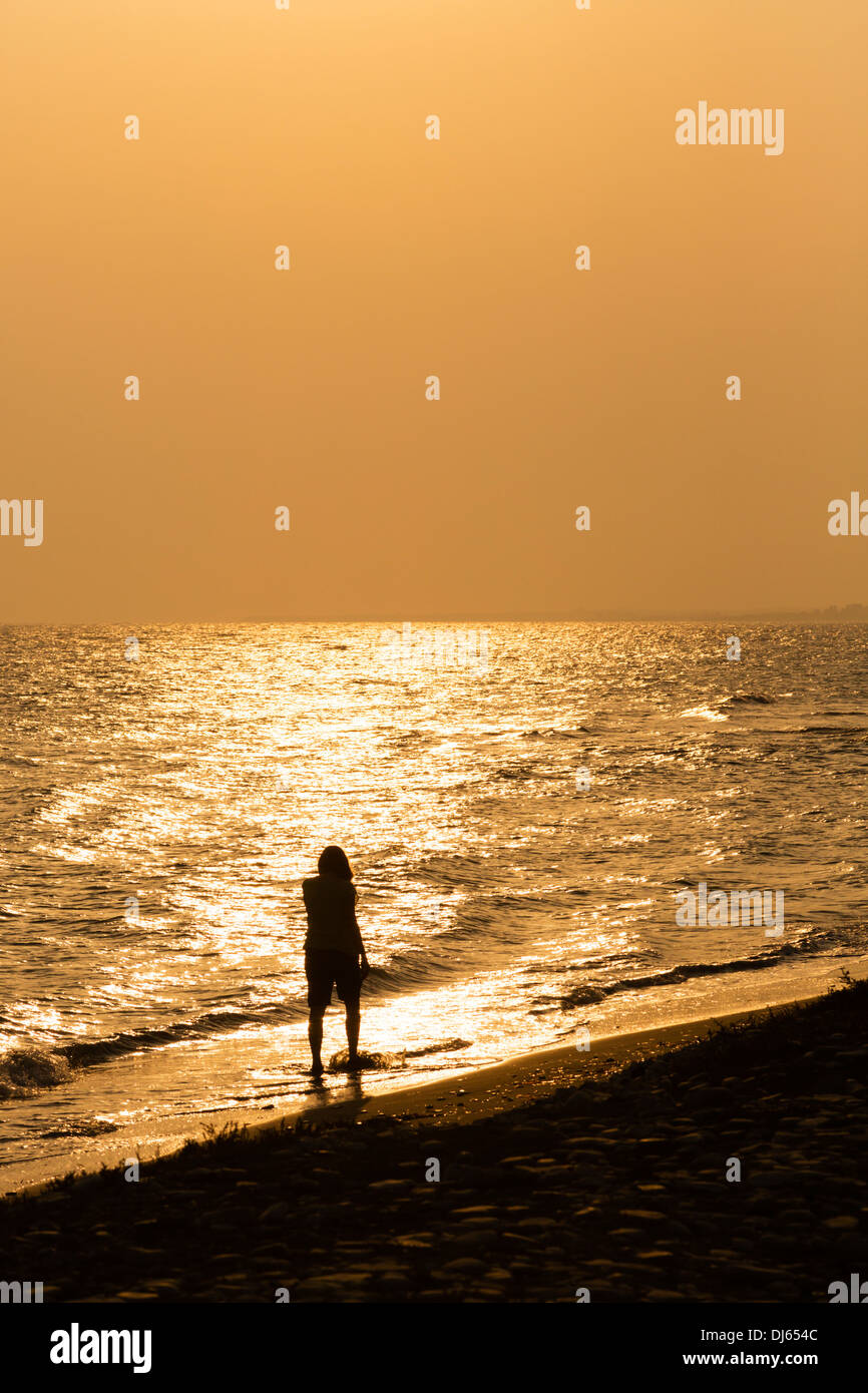 Frau am Strand, Hintergrundbeleuchtung durch tiefstehende Sonne. Zypern Stockfoto