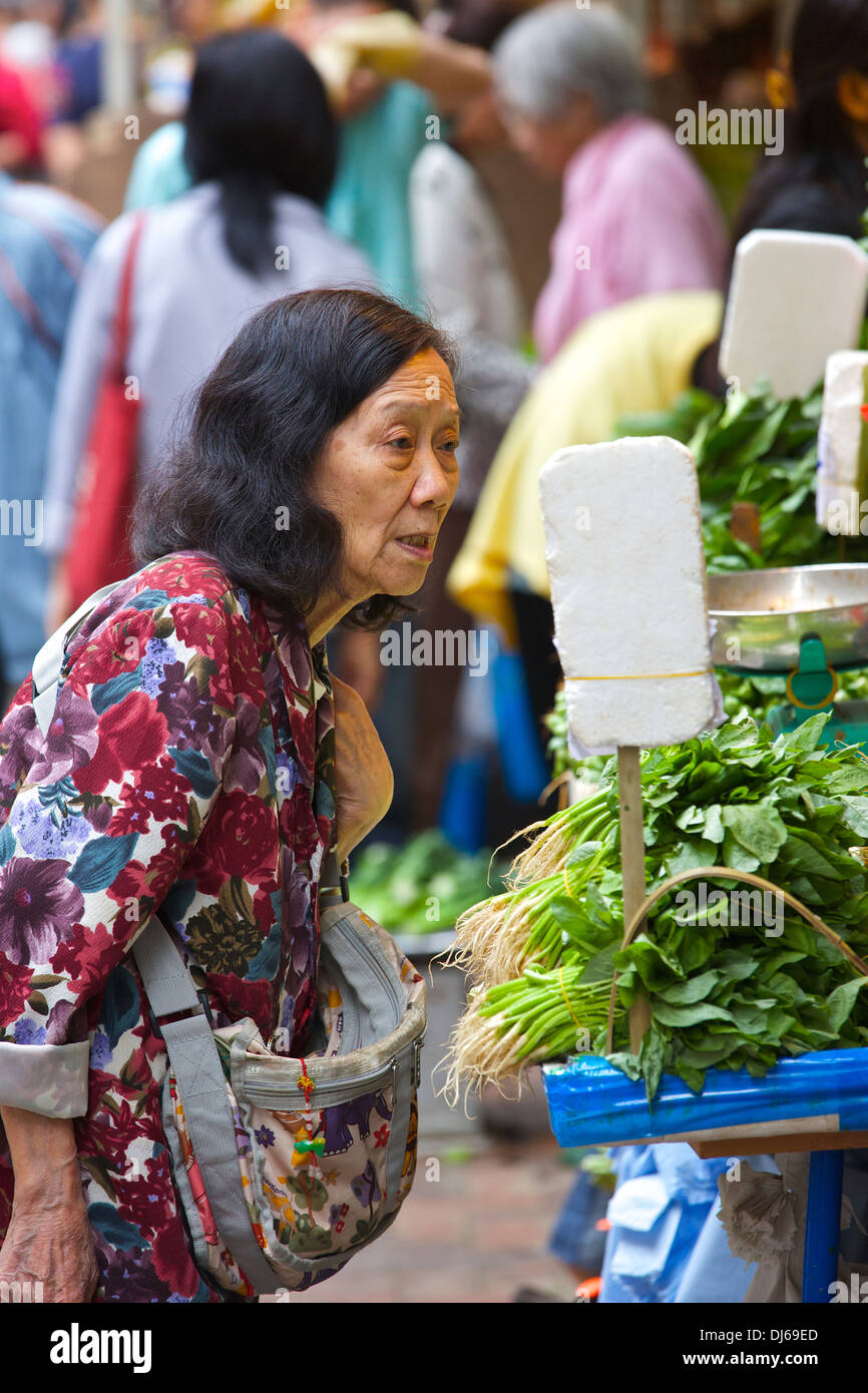 Eine chinesische alte Dame kauft ihre Lebensmittel auf dem Bowrington Markt, Hong Kong. Stockfoto