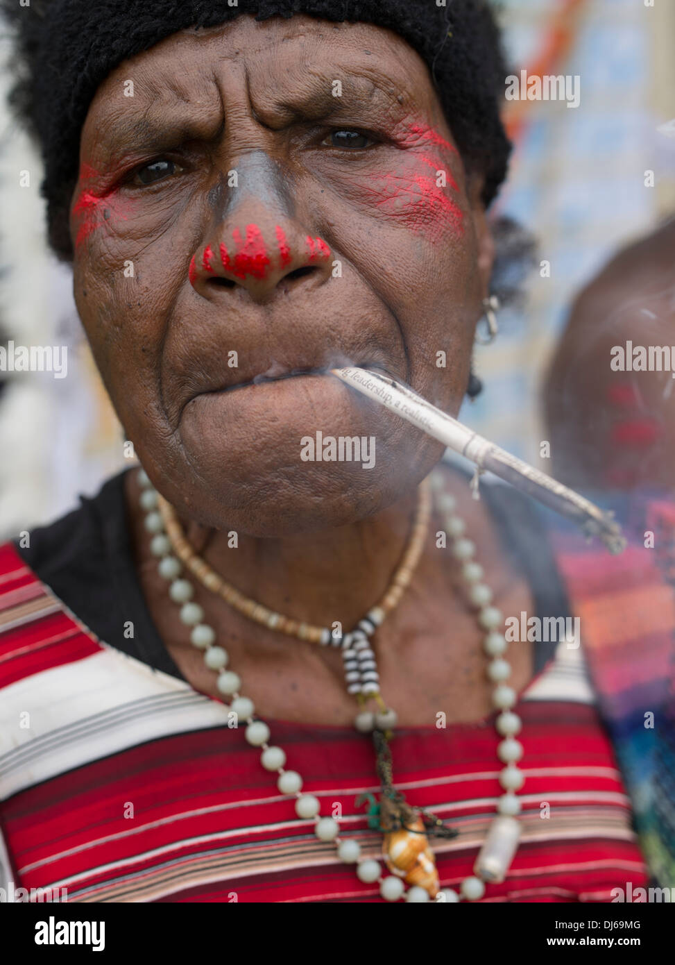 Ältere Frau Singsing Fraktion, Goroka Show, Papua New Guinea Rauchen handmade Tabak-Zigarette Stockfoto