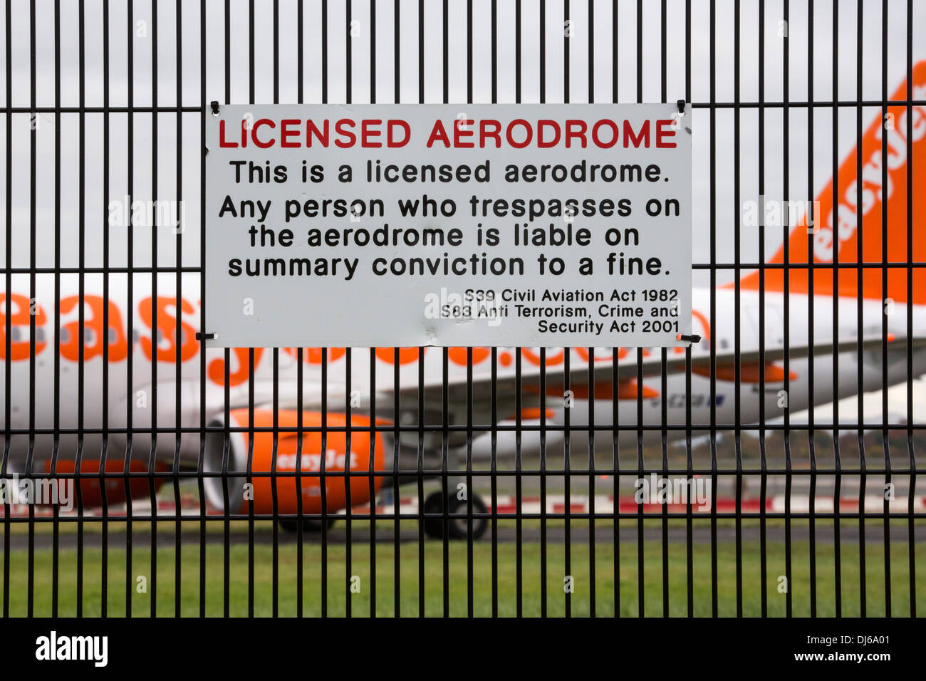 Schilder am Sicherheitszaun am Flughafen Manchester, UK mit dem Flugzeug hinter. Stockfoto