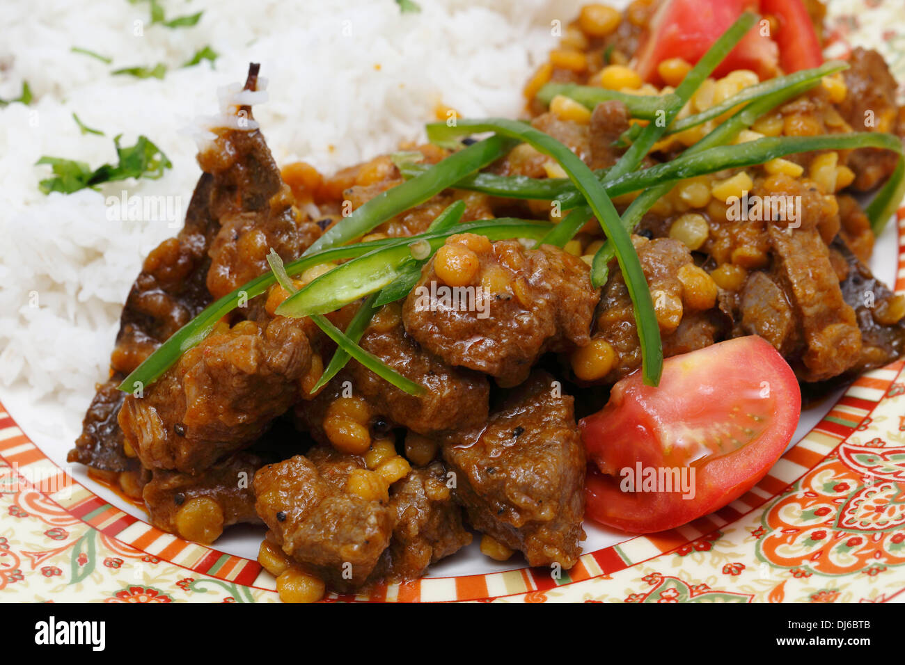 Lahore (Pakistan) Lamm und Chana Dhal (Split Pea) Curry, garniert mit Tomaten und Chilischoten, und mit Reis serviert. Stockfoto