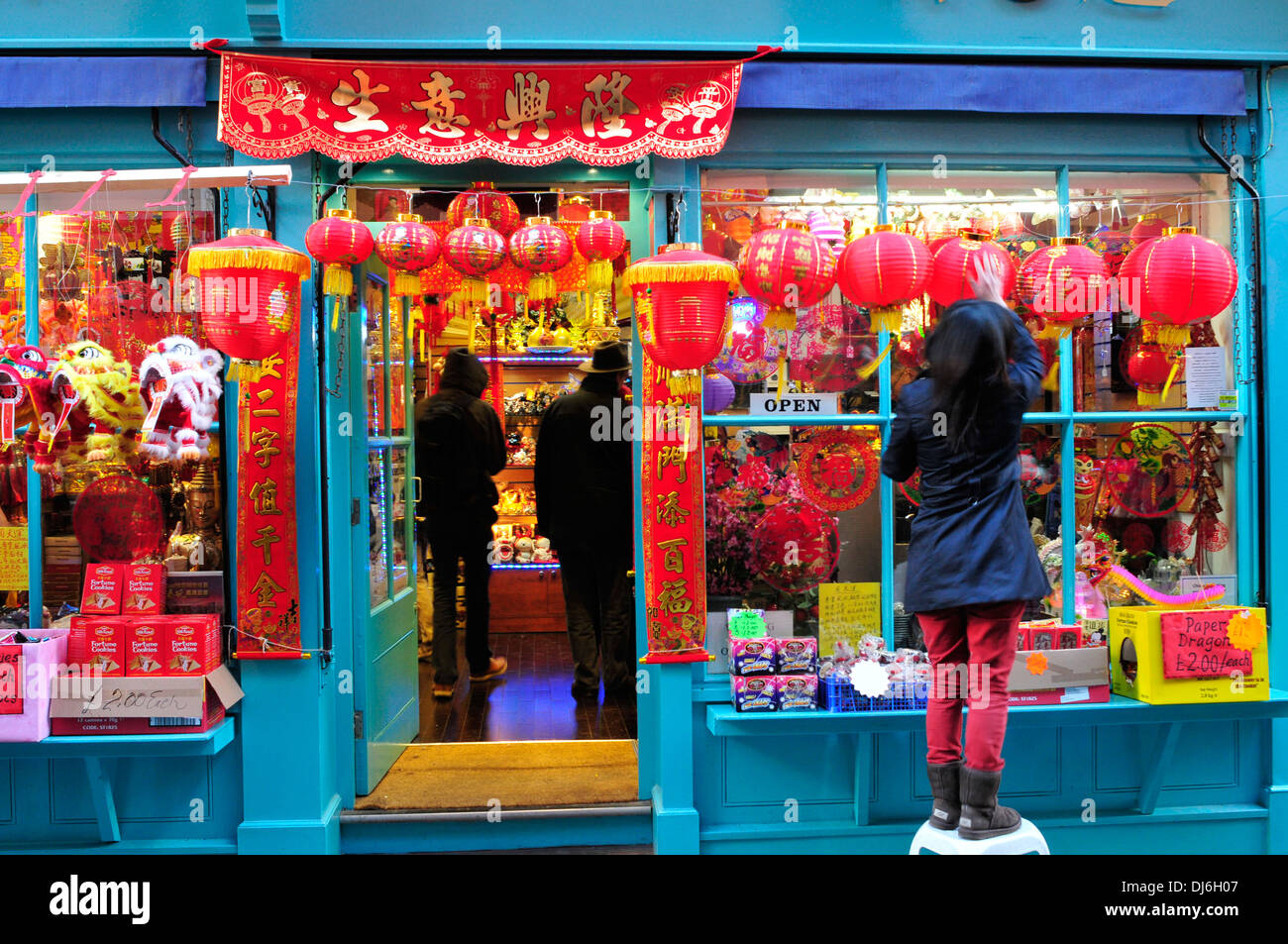Eine Frau setzt Dekorationen auf ein Geschäft, in Vorbereitung für Chinese New year Stockfoto