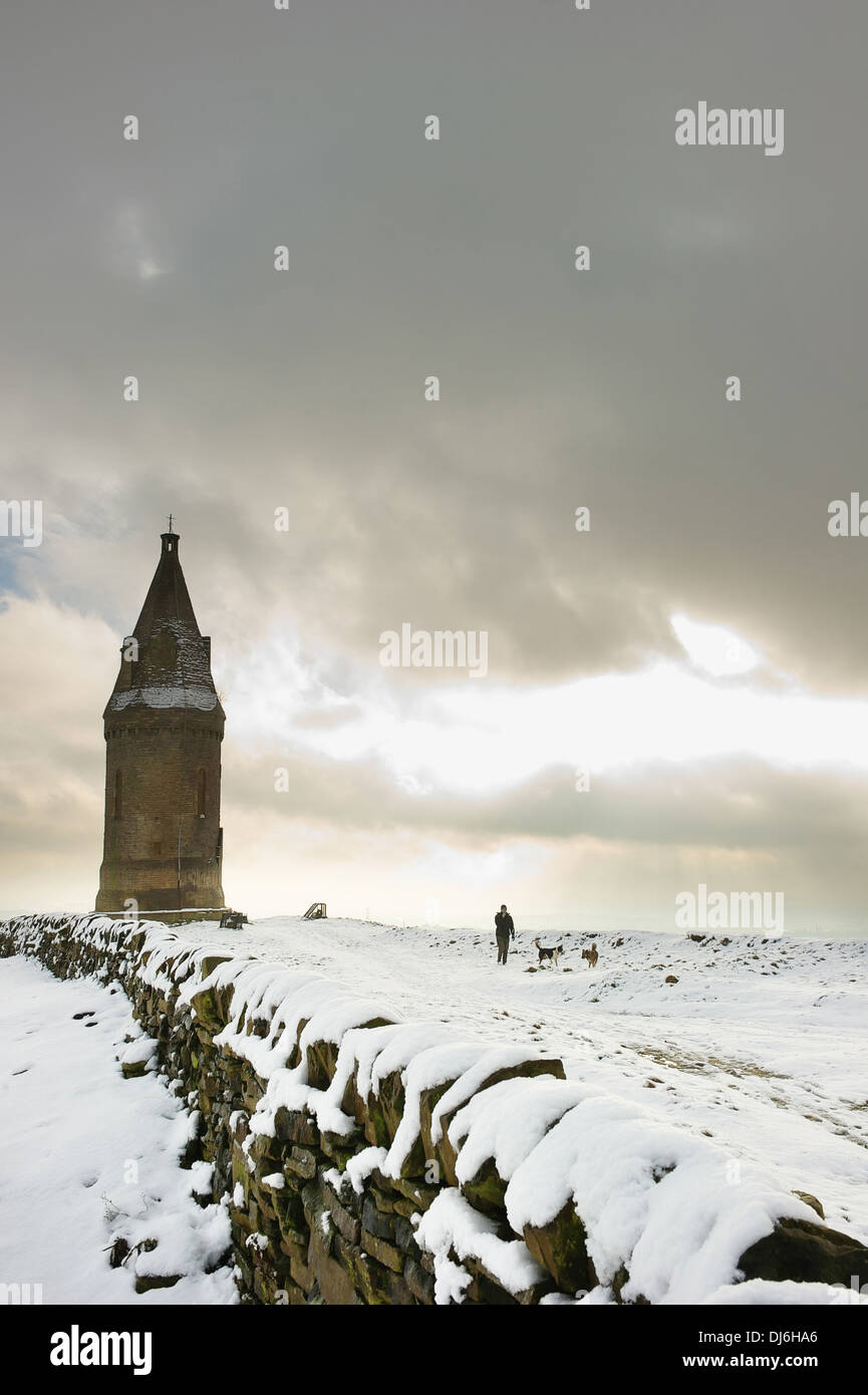 Ein Mann, der Hunde im Schnee in der Nähe von Hartshead Pike, Ashton-under-Lyne, Greater Manchester. Stockfoto