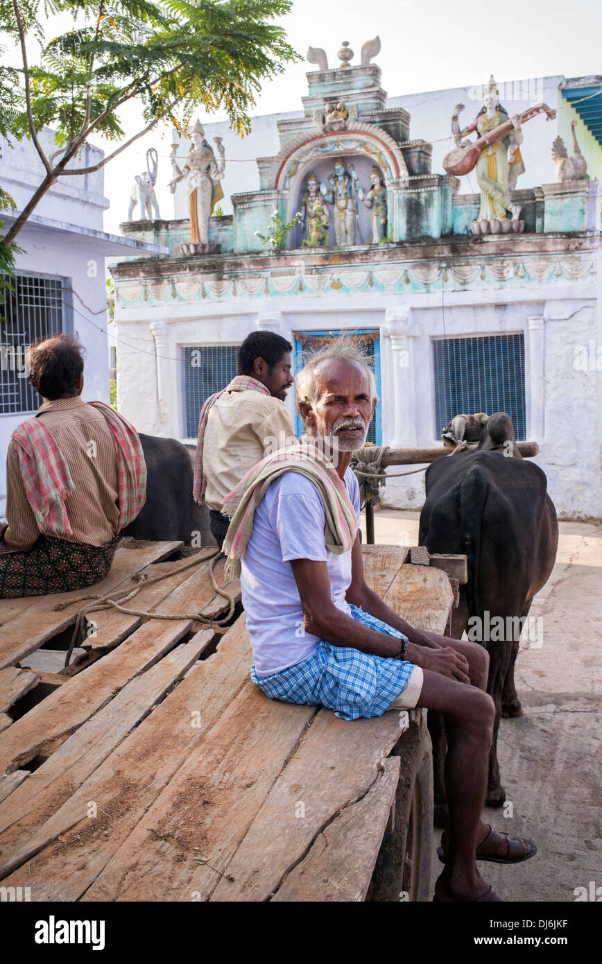 Südindische Männer auf einem Ochsenkarren vor einem hindu Tempel in einem indischen Dorf. Andhra Pradesh, Indien Stockfoto