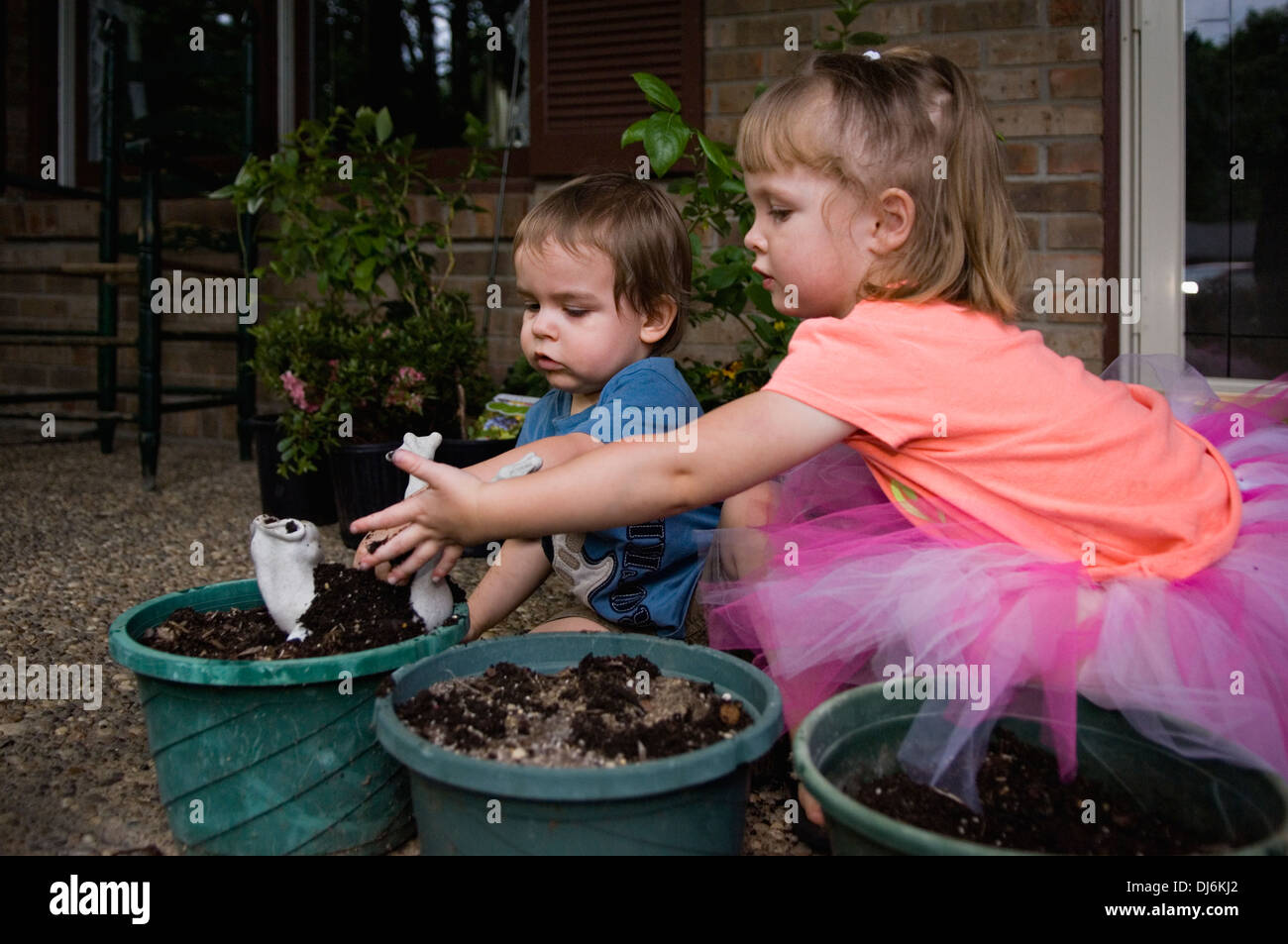 Drei Jahre altes Mädchen und zwei Jahre alten Jungen spielen mit dem Boden in Gartenarbeit Töpfen Stockfoto
