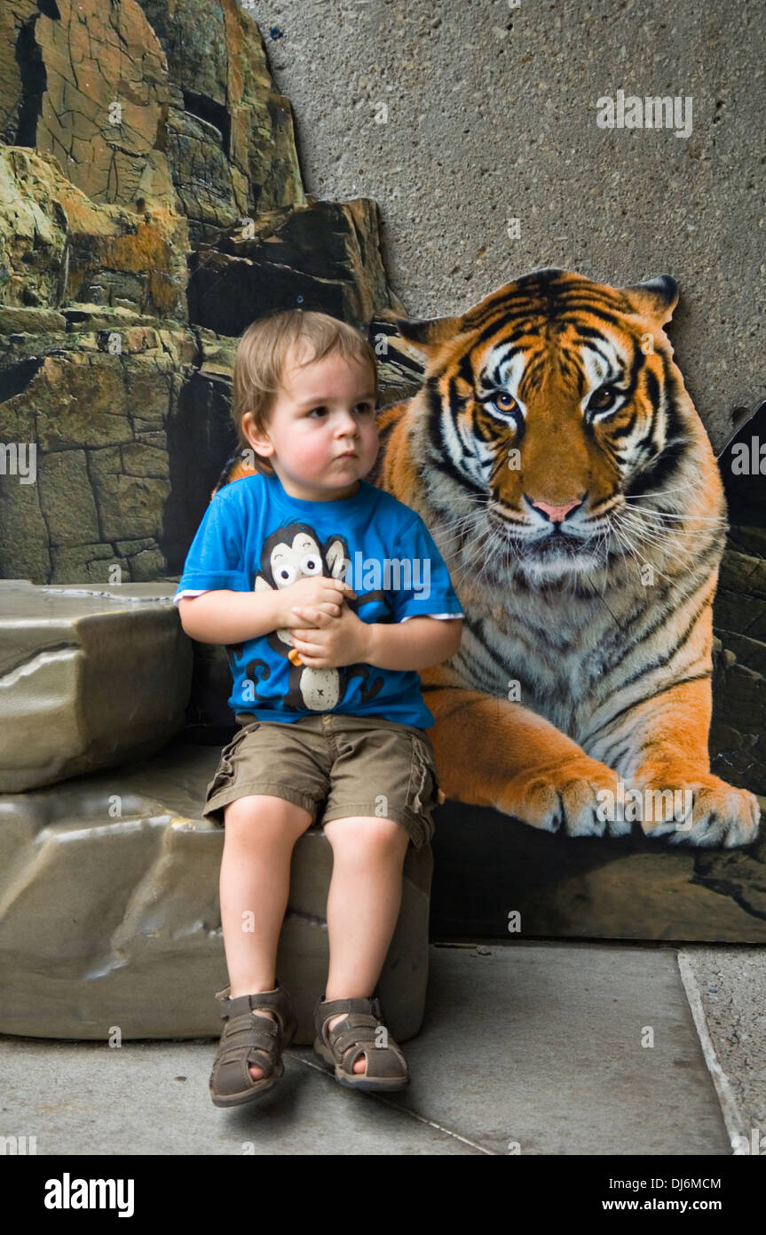 Kleinkind sitzen neben Bild eines Tigers im Louisville Zoo in Louisville, Kentucky Stockfoto