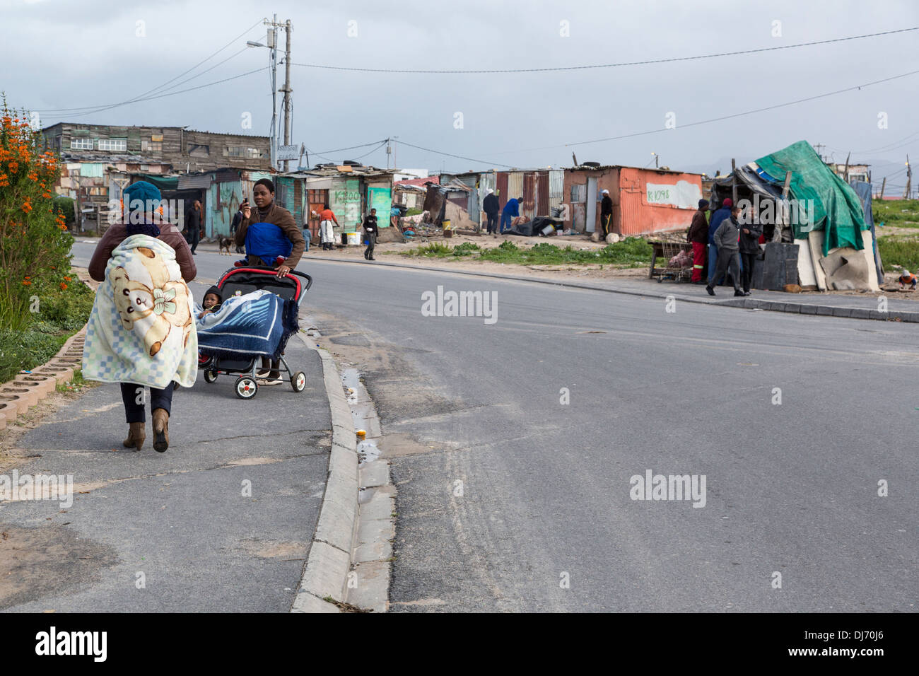 Südafrika, Cape Town, Guguletu Township Straßenszene. Frau mit Baby auf Rücken, Frau schob Baby in einem Kinderwagen (Kinderwagen). Stockfoto