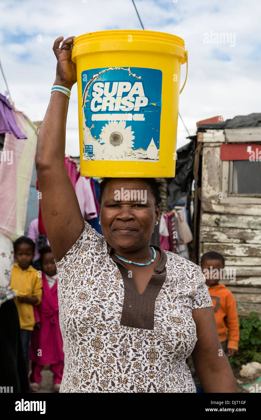 Südafrika, Cape Town, Guguletu Township. Frau trägt Wasser aus öffentlichen Tippen Sie auf in ihr Haus. Stockfoto