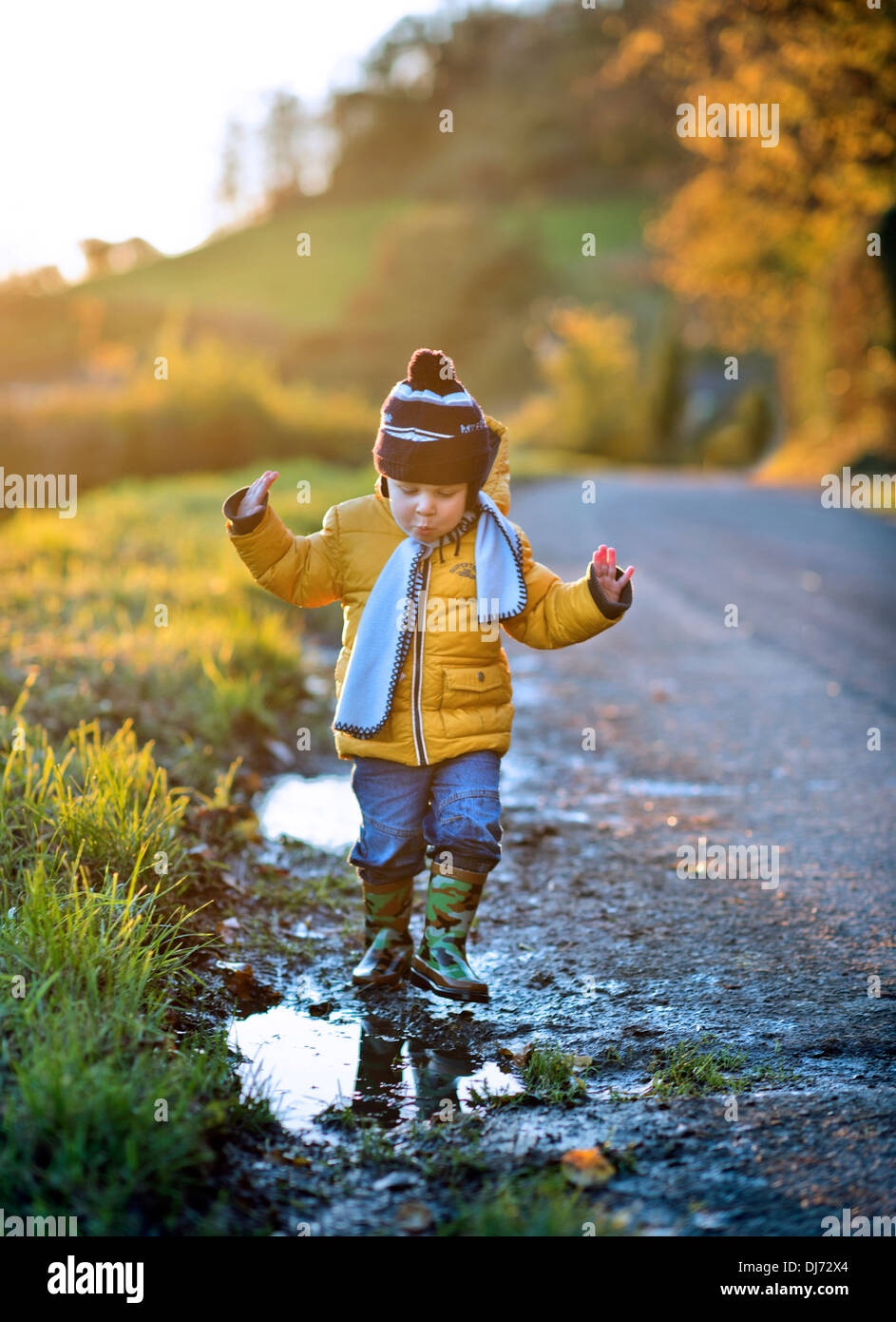 Ein kleiner Junge, an einem kalten Abend findet eine Pfütze UK Stockfoto