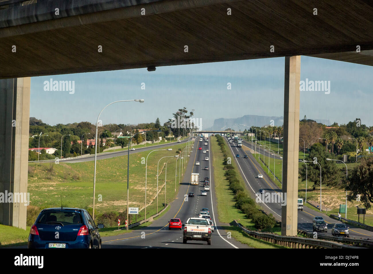 Südafrika, Cape Town. Autobahn in Richtung Kapstadt. Fahren auf der linken Seite. Tafelberg in der Ferne. Stockfoto
