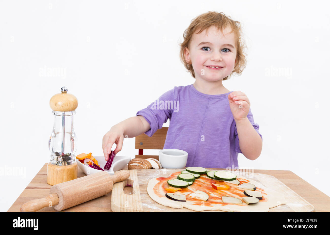 niedliche Mädchen sitzt hinter der Rezeption Pizzabacken. Studio in grauem Hintergrund gedreht Stockfoto