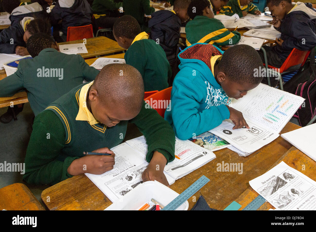 Südafrika, Cape Town, Guguletu Township. Young Boys die Intshinga Primary School in ihre Arbeitsmappen in englischer Sprache arbeiten. Stockfoto