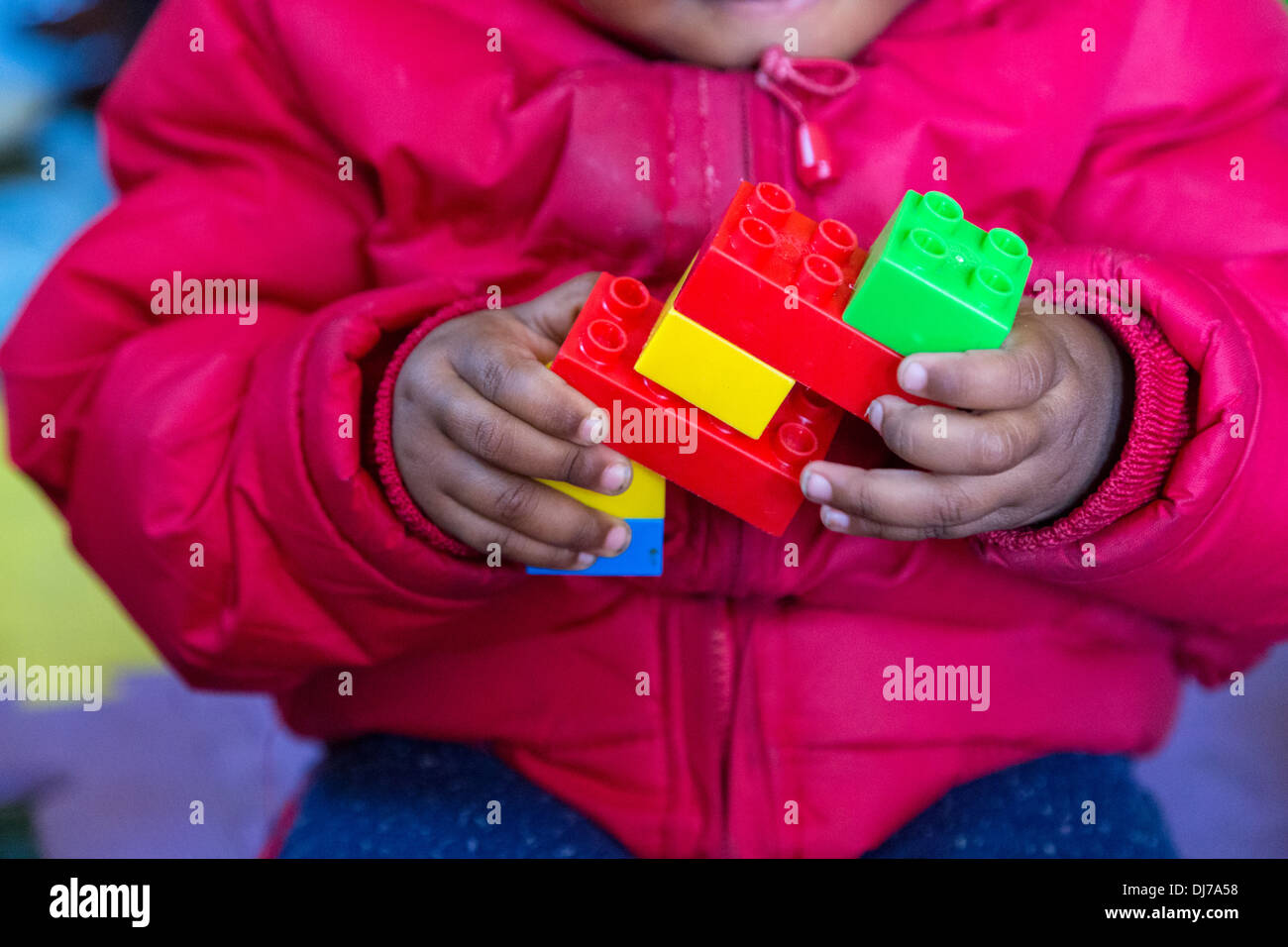 Südafrika, Cape Town. Kleines Kind Montage Kunststoff-Konstruktion-Stücke in einer Kindertagesstätte für Kleinkinder. Stockfoto