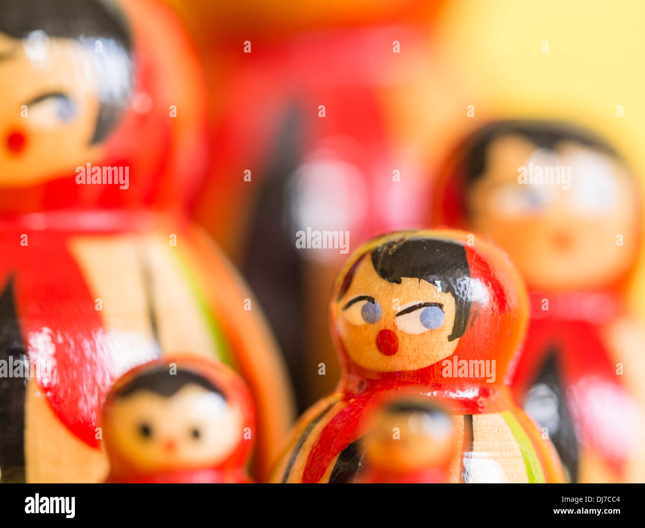 Gruppe von russischen Matroschka Puppen in einer Gruppe mit selektiven Fokus auf eine Puppe, umrahmt von einem hellgelben Hintergrund. Stockfoto