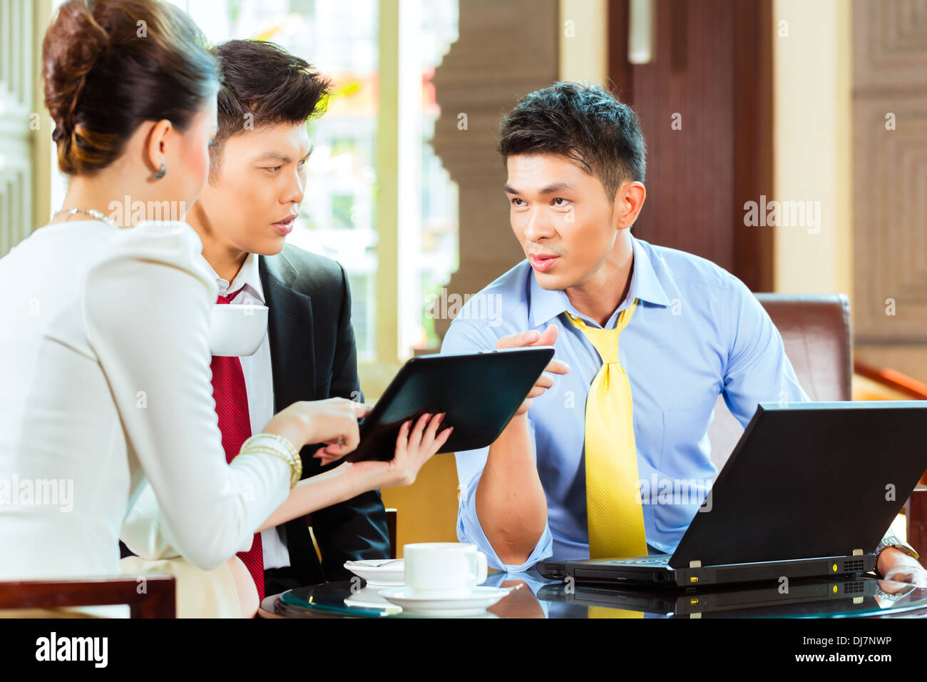 Drei asiatische chinesische Büro Menschen oder Geschäftsleute und Geschäftsfrau, die ein Geschäftstreffen in einer Hotel-Lobby-diskutieren Stockfoto