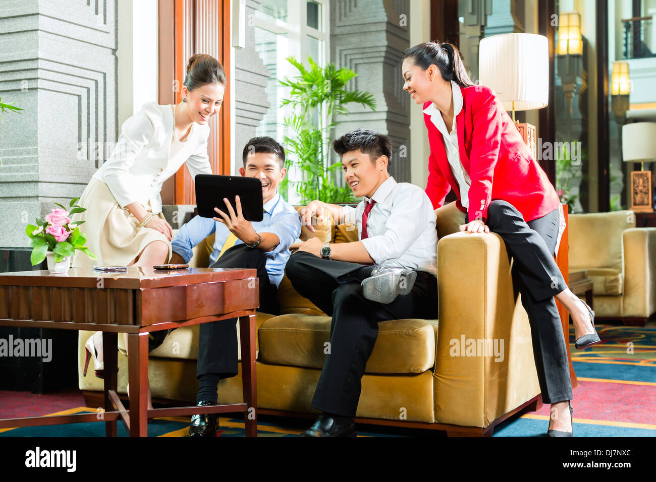Gruppe von vier asiatische chinesische Geschäftsleute treffen für Business-Diskussion in einer luxuriösen Hotel-Lobby, Diskussionspapieren Stockfoto