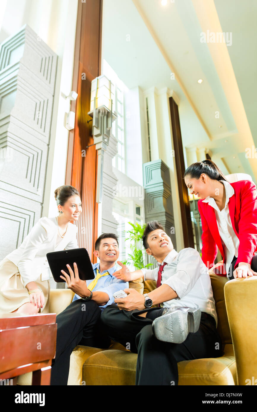 Gruppe von vier asiatische chinesische Geschäftsleute treffen für Business-Diskussion in einer luxuriösen Hotel-Lobby, Diskussionspapieren Stockfoto