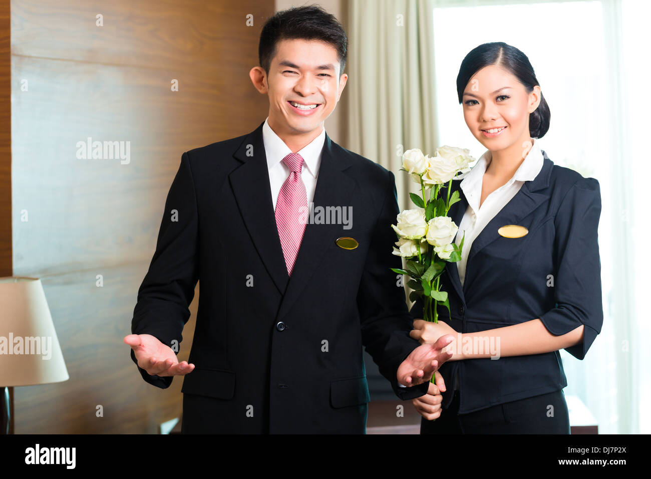 Hotel-Manager oder Direktor und Supervisor begrüßen ankommende VIP-Gäste mit Rosen bei der Ankunft im grand Hotel oder Luxus Stockfoto