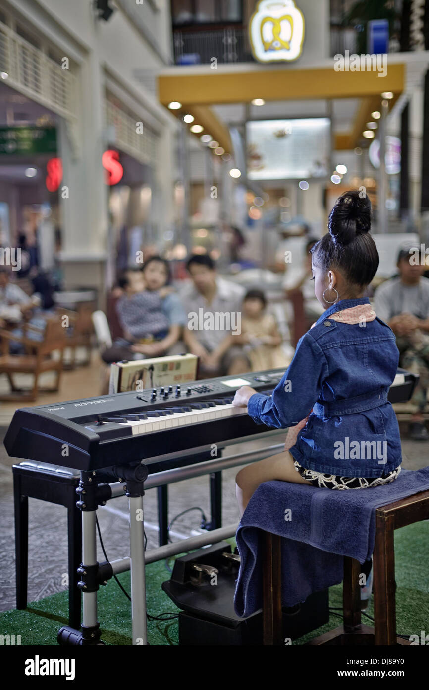 Das 7-jährige thailändische Kind spielt in einem Einkaufszentrum mit elektrischem Klavier. Thailand S. E. Asien Stockfoto