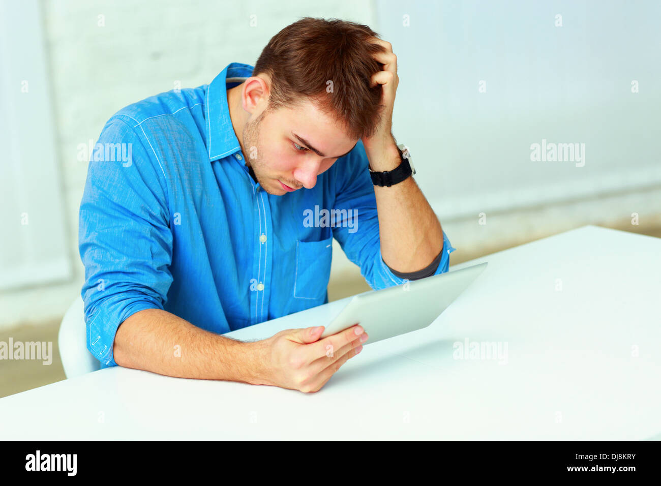 Nachdenklich lässig Jungunternehmer Blick auf den Tablet-Computer im Büro Stockfoto