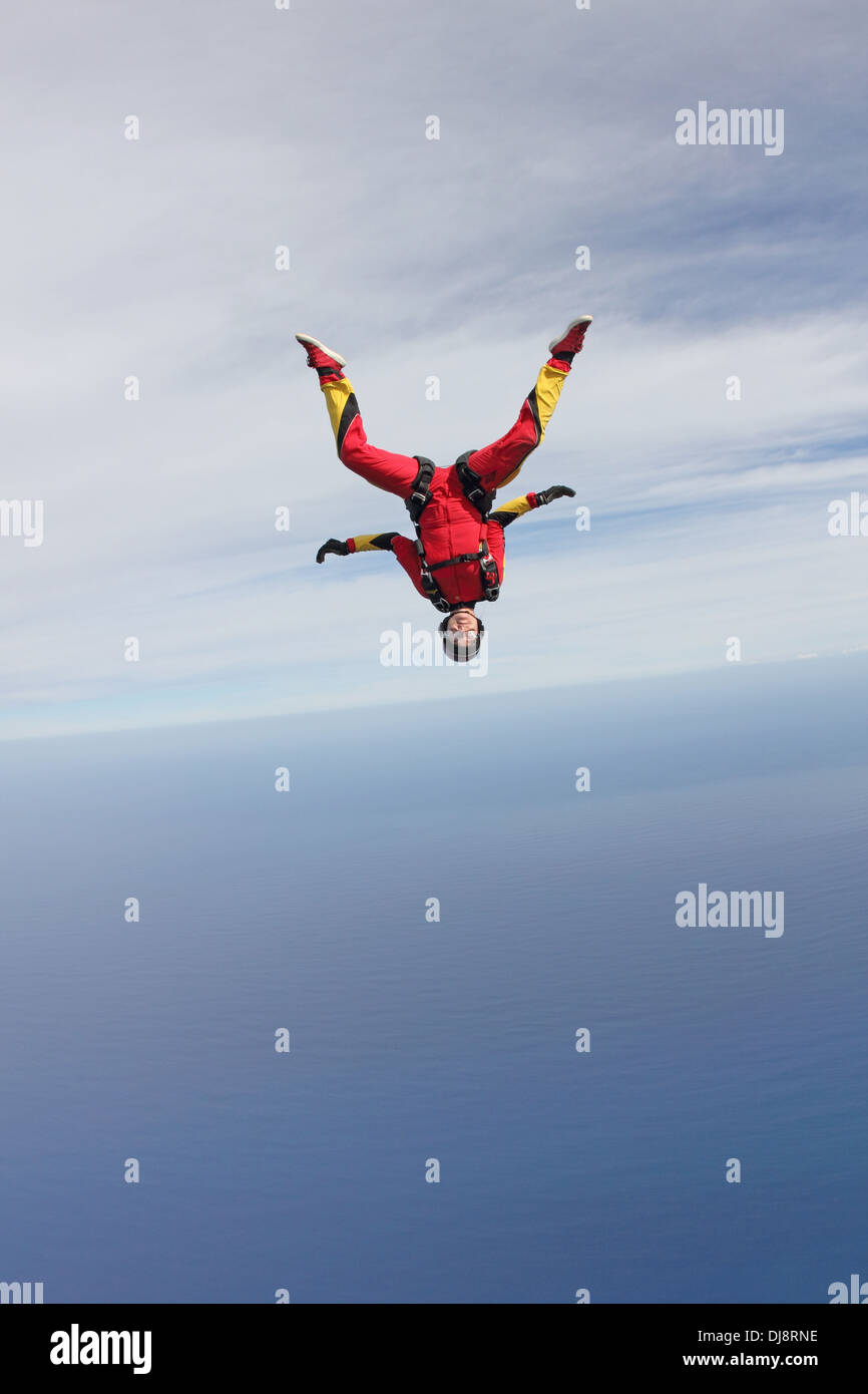 Dieses Fallschirmspringer Mädchen fliegt in einen Kopf nach unten über das tiefblaue Meer unter bewölktem Himmel. Sie ist mit 130 km/h schnell fliegen. Stockfoto